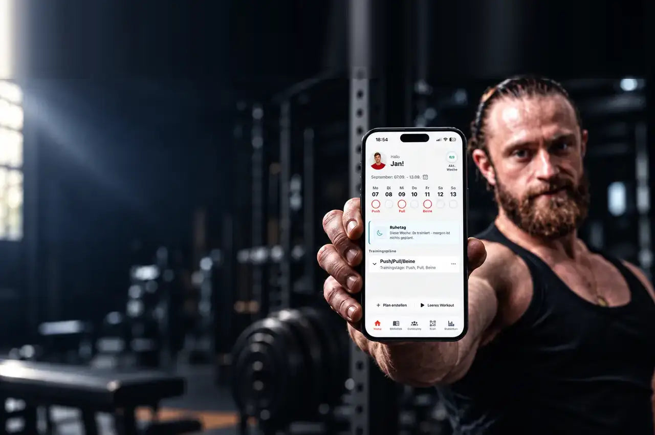 Trainings-App f&uuml;r Krafttraining: Person im Gym h&auml;lt ein iPhone mit der StrongNotes App, auf dem Bildschirm die Trainingswoche aus Push, Pull und Beine.